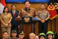 Airlangga Hartarto, Menko Perekonomian, memimpin konferensi pers pengumuman pencairan THR dan BHR Idulfitri 2026. THR diberikan kepada ASN, TNI, Polri, pensiunan, dan pekerja ojek online. Suasana terlihat ceria, dengan sejumlah penerima memegang amplop berisi THR.

Sumber Foto: Hasil ilustrasi berbasis informasi publik, tidak diambil dari sumber resmi.