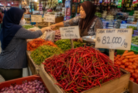 Pedagang melayani pembeli di pasar tradisional dengan tumpukan cabai rawit merah yang mengalami kenaikan harga hingga mencapai Rp82 ribu per kilogram. Kenaikan harga pangan menjadi perhatian masyarakat karena berdampak langsung pada kebutuhan sehari-hari.